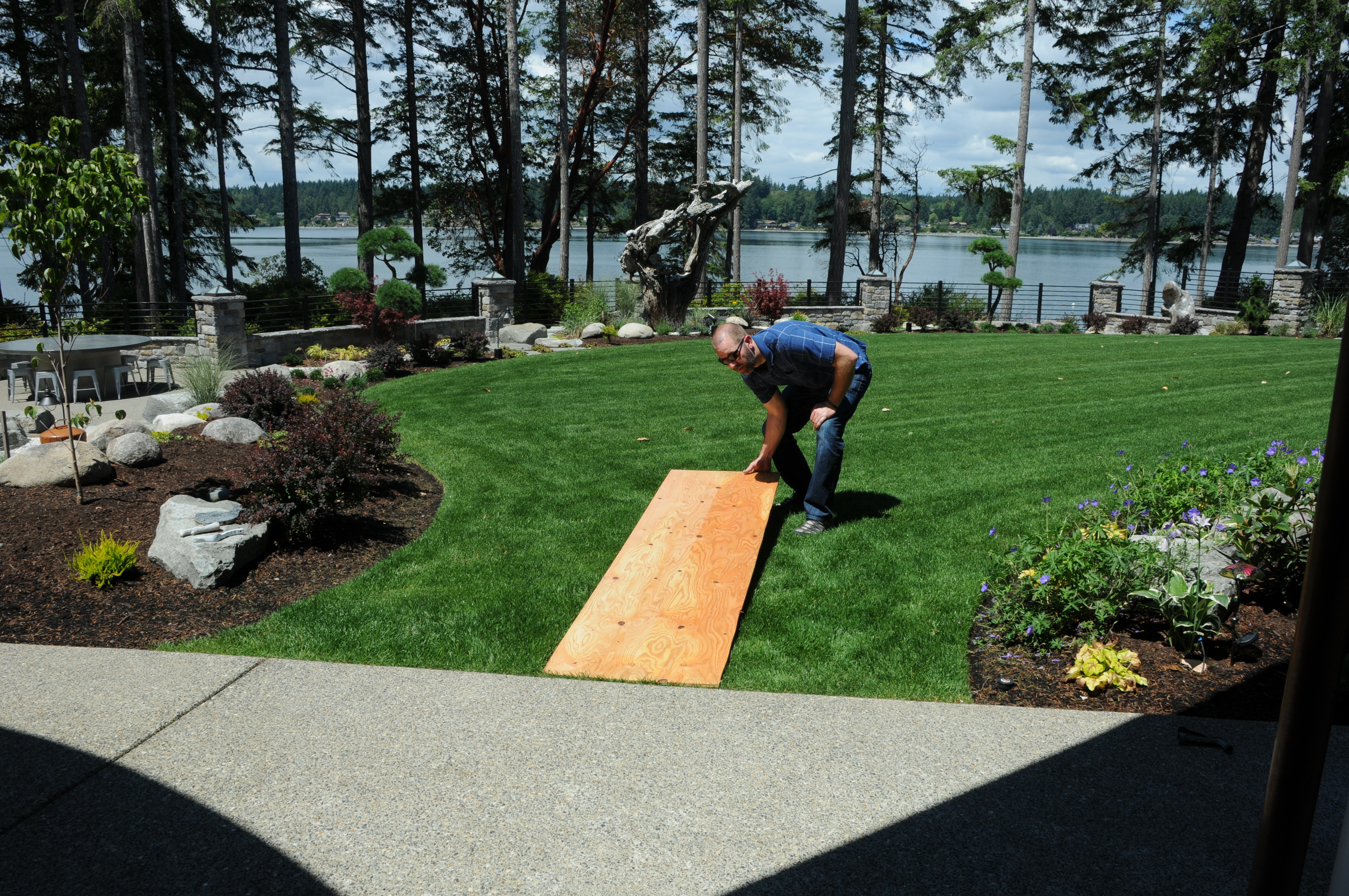 Man placing 2 foot by 8 foot board on lawn