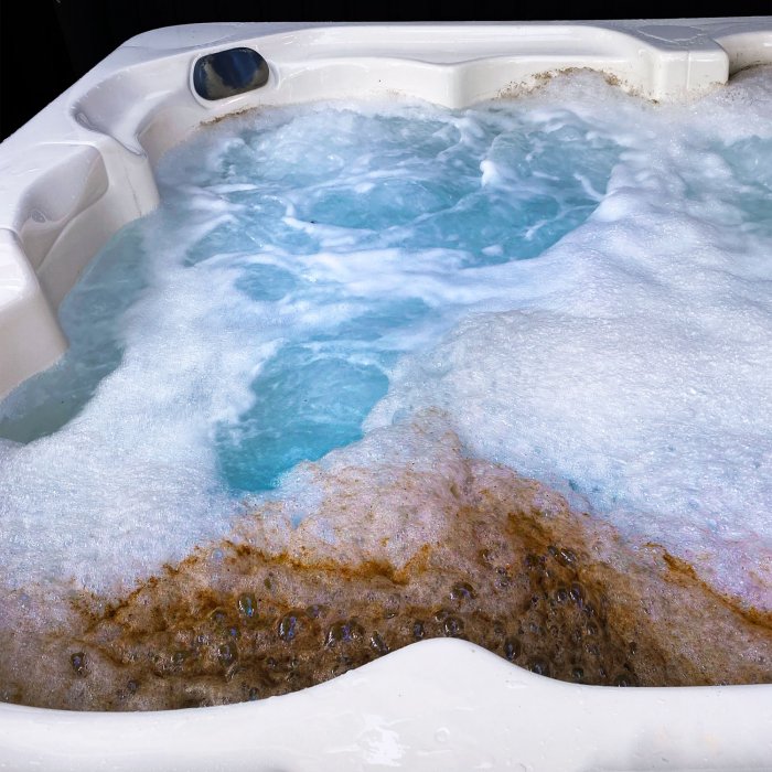 White hot tub with scummy biofilm floating on top of the water